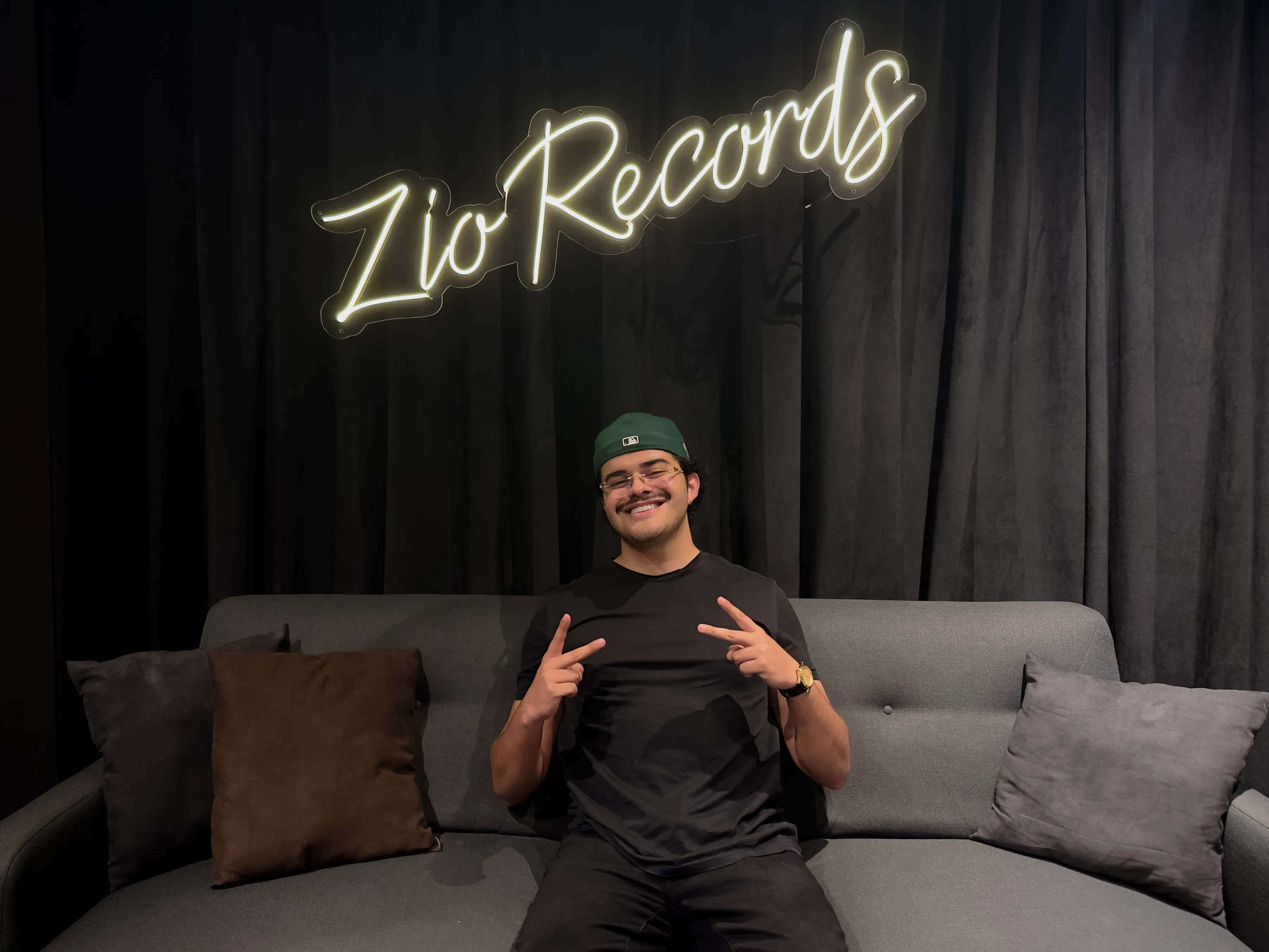 Mikezio sentado en el sillón de su estudio con el logo de Zio Records atrás.